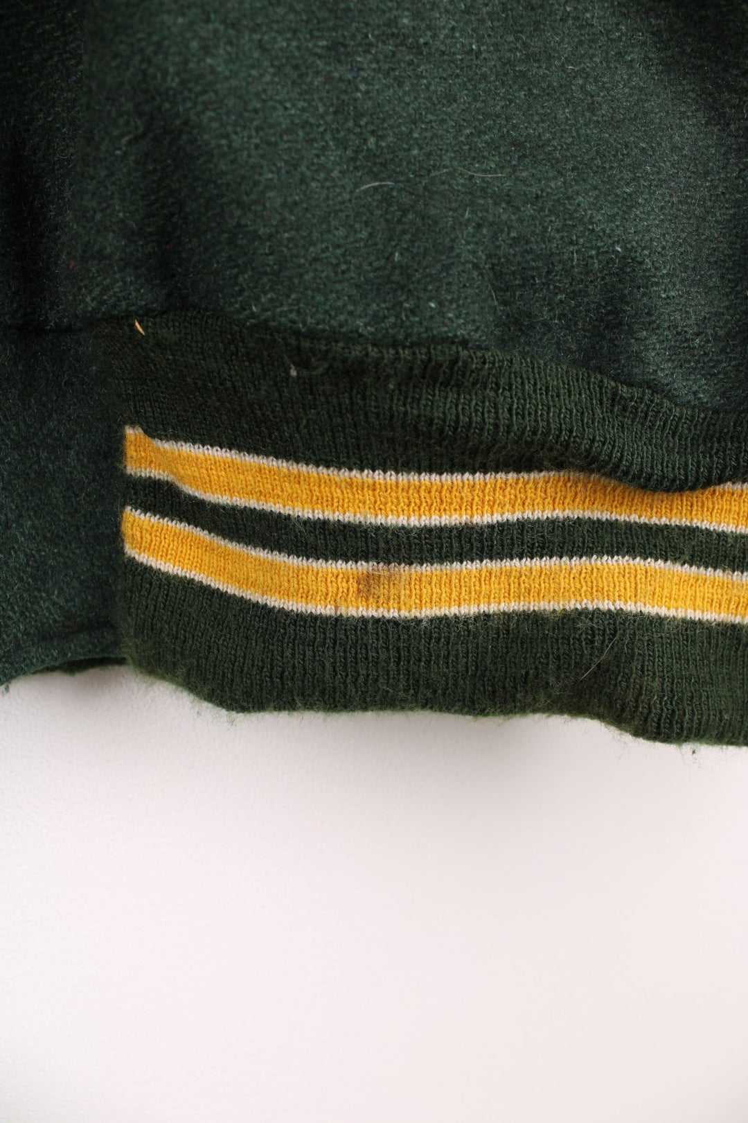 Vintage Delong, Placer Hillmen Wrestling varsity jacket in green and yellow, with beige leather sleeves and snap fastenings. Features embroidered letterman patch and numbers on the sleeve. 