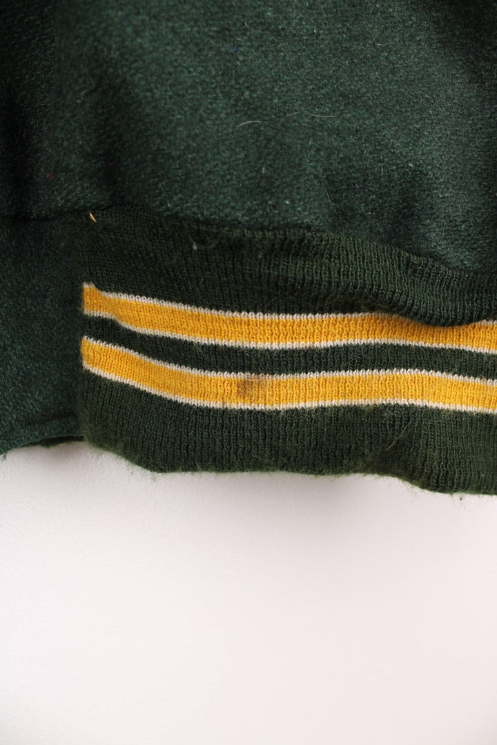 Vintage Delong, Placer Hillmen Wrestling varsity jacket in green and yellow, with beige leather sleeves and snap fastenings. Features embroidered letterman patch and numbers on the sleeve. 