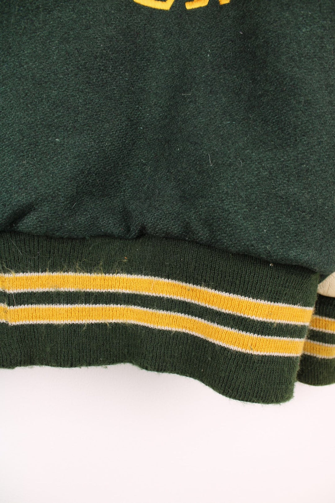 Vintage Delong, Placer Hillmen Wrestling varsity jacket in green and yellow, with beige leather sleeves and snap fastenings. Features embroidered letterman patch and numbers on the sleeve. 