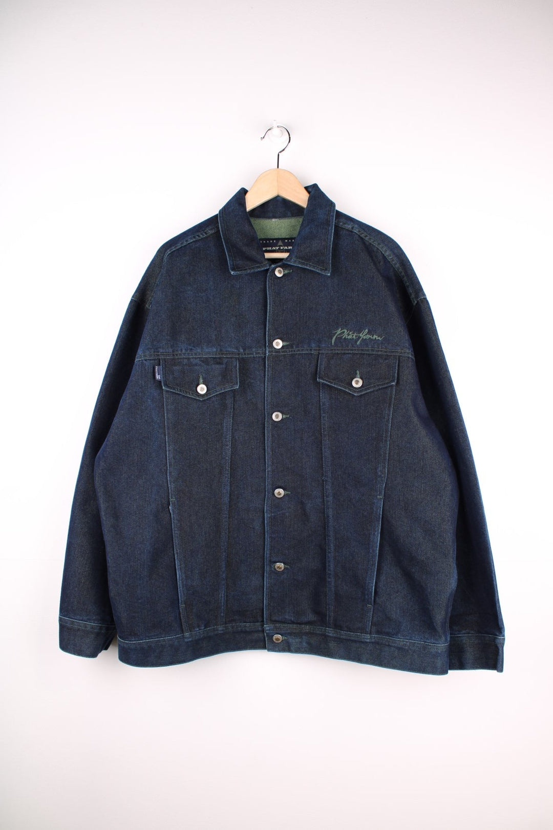 Vintage denim jacket in a dark indigo blue colourway. The jacket has two front packets, and an embroidered logo on the chest panel. On the yoke is a small Phat Farm embroidered patch. The back hem has a leather denim label stitched on.  