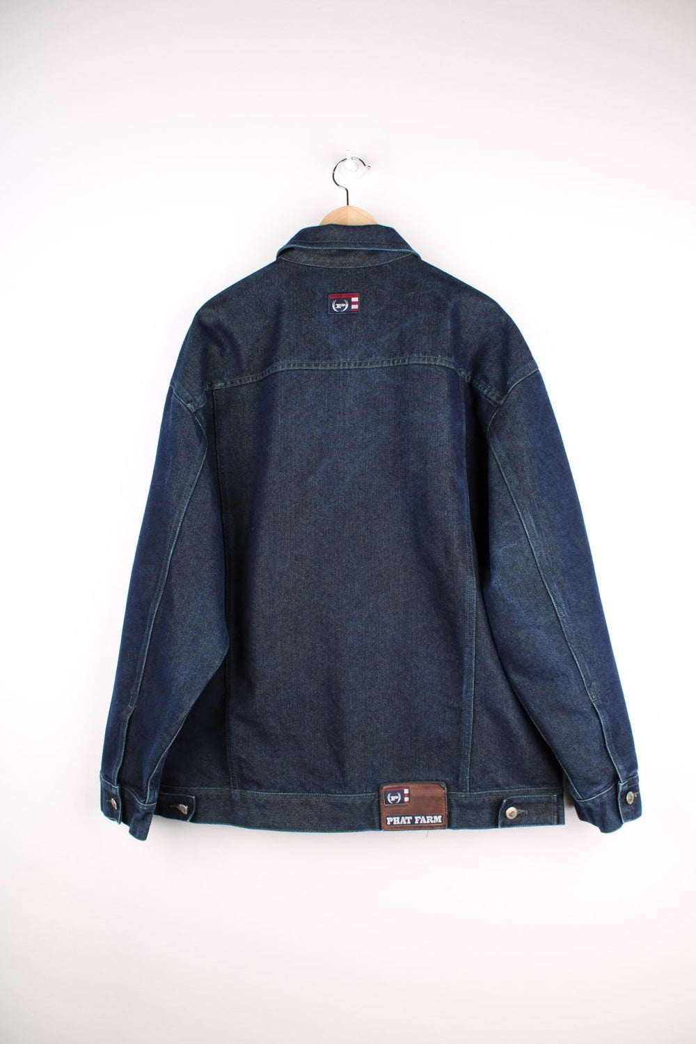 Vintage denim jacket in a dark indigo blue colourway. The jacket has two front packets, and an embroidered logo on the chest panel. On the yoke is a small Phat Farm embroidered patch. The back hem has a leather denim label stitched on.  