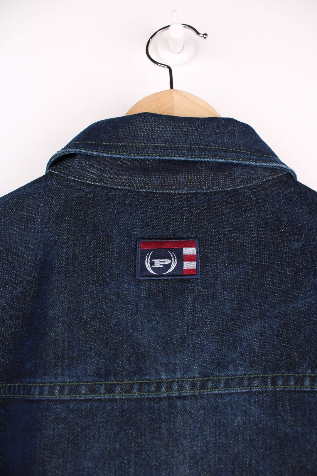 Vintage denim jacket in a dark indigo blue colourway. The jacket has two front packets, and an embroidered logo on the chest panel. On the yoke is a small Phat Farm embroidered patch. The back hem has a leather denim label stitched on.  