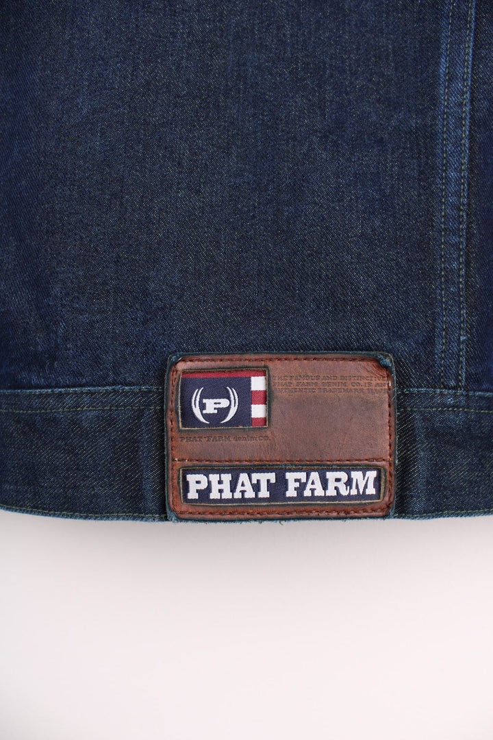 Vintage denim jacket in a dark indigo blue colourway. The jacket has two front packets, and an embroidered logo on the chest panel. On the yoke is a small Phat Farm embroidered patch. The back hem has a leather denim label stitched on.  