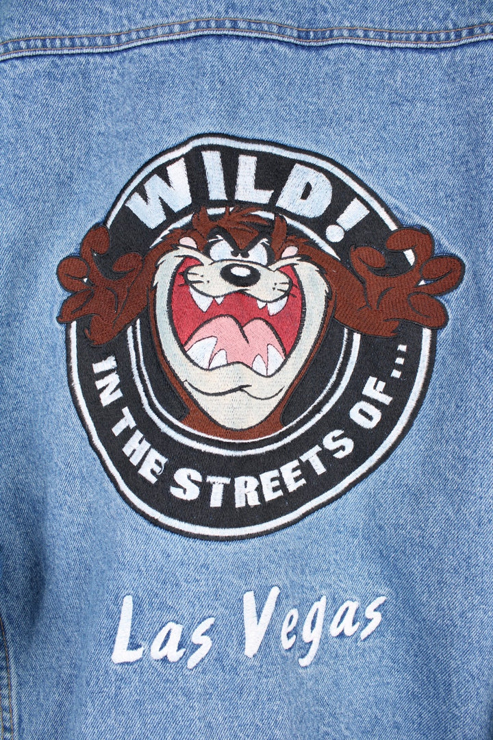 Vintage 1996 Warner Bros Vintage jacket in a mid blue denim colourway. The jacket closes with looney tunes silver buttons, has four front pockets and a large Taz embroidered patch on the back. The patch has some slight discolouration as seen from the photos. 