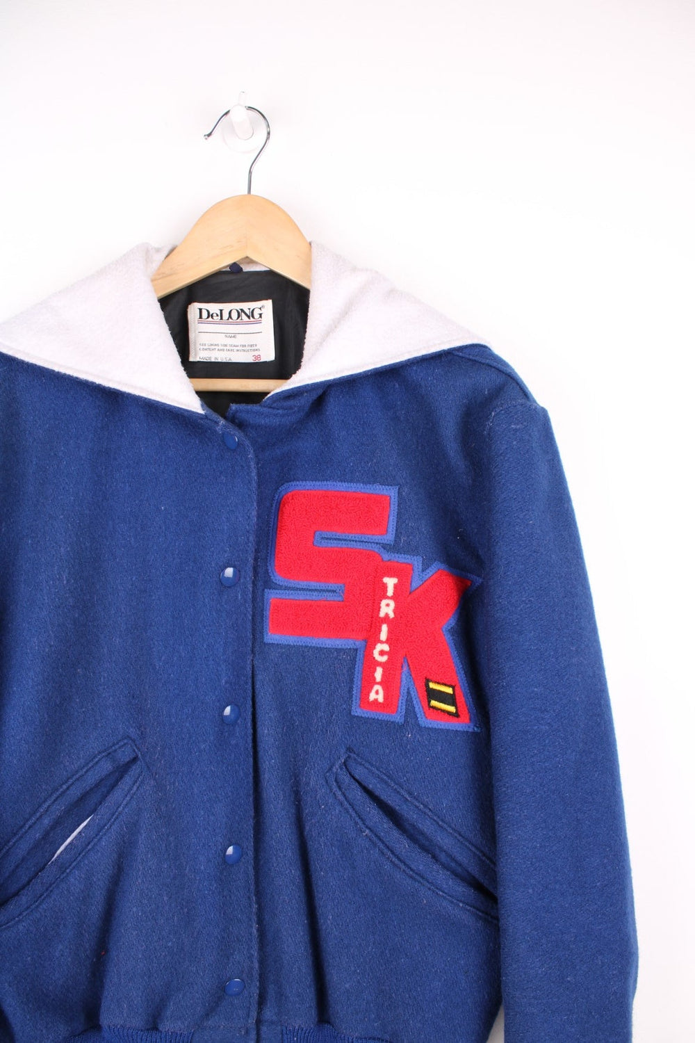 Vintage Delong varsity jacket in blue with red letterman patches, snap fastenings, and flap hood with embroidered "Drill Team".