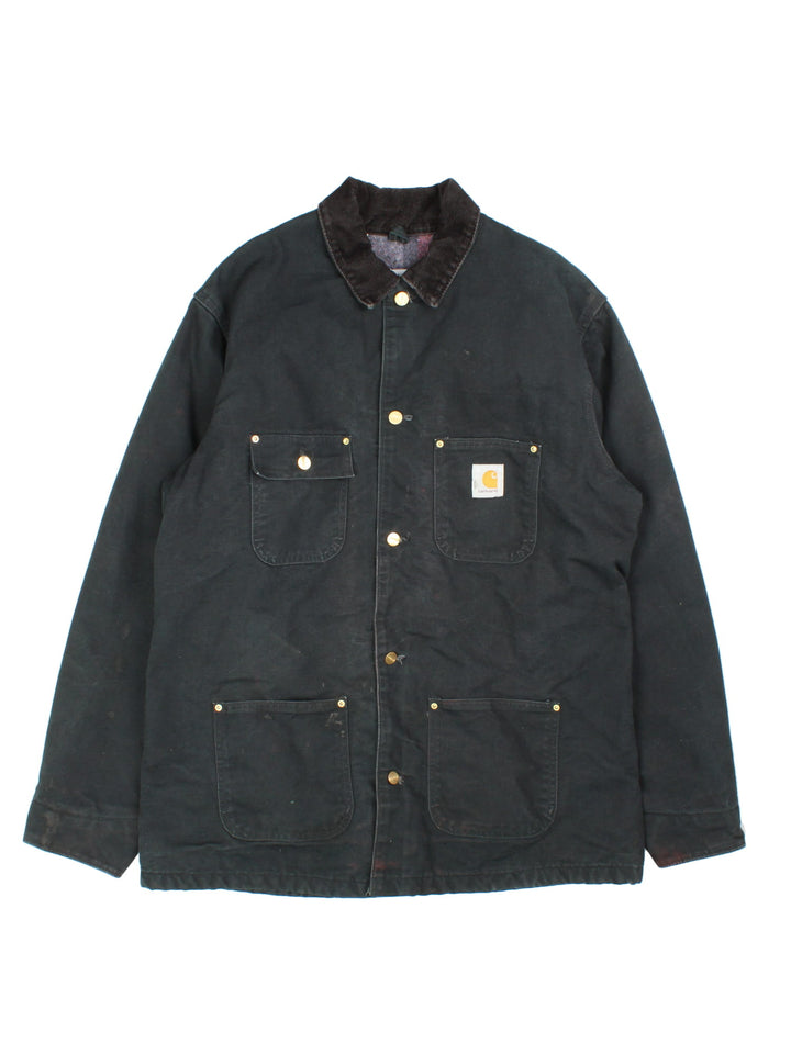  1990s Carhartt Chore jacket in a black colourway. The jacket has a corduroy collar, is blanket lined and has multiple pockets on the exterior and one on the interior. There is a stitched logo on the front pocket, and gold hardware. 