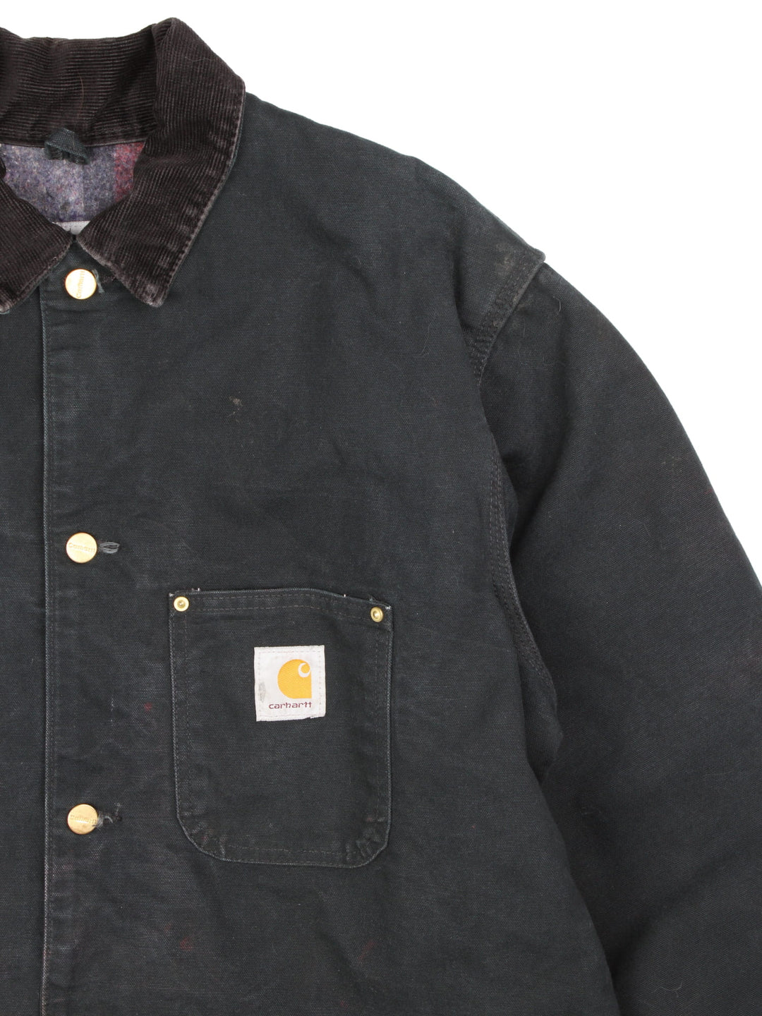  1990s Carhartt Chore jacket in a black colourway. The jacket has a corduroy collar, is blanket lined and has multiple pockets on the exterior and one on the interior. There is a stitched logo on the front pocket, and gold hardware. 