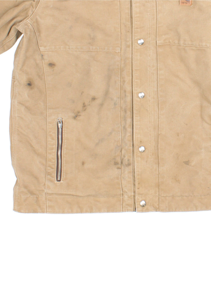 Carhartt J285 FRB Frontier Chore jacket in a tan colourway. The jacket has multiple pockets on the exterior with zip closures, and two interior pockets. There is a contrasting collar, and silver hardware. 