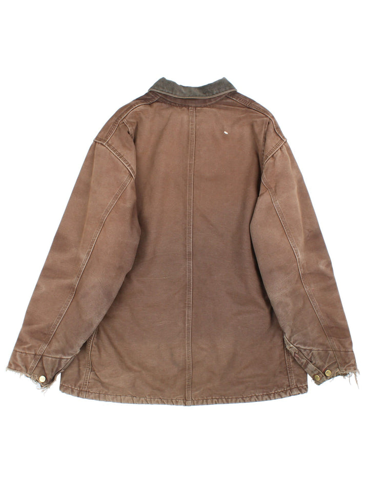 Vintage Carhartt Chore Coat in a brown colourway. The jacket has multiple exterior pockets, and one interior. It is blanket lined and has a corduroy collar. There is a leather logo patch stitched onto the front, and gold hardware.