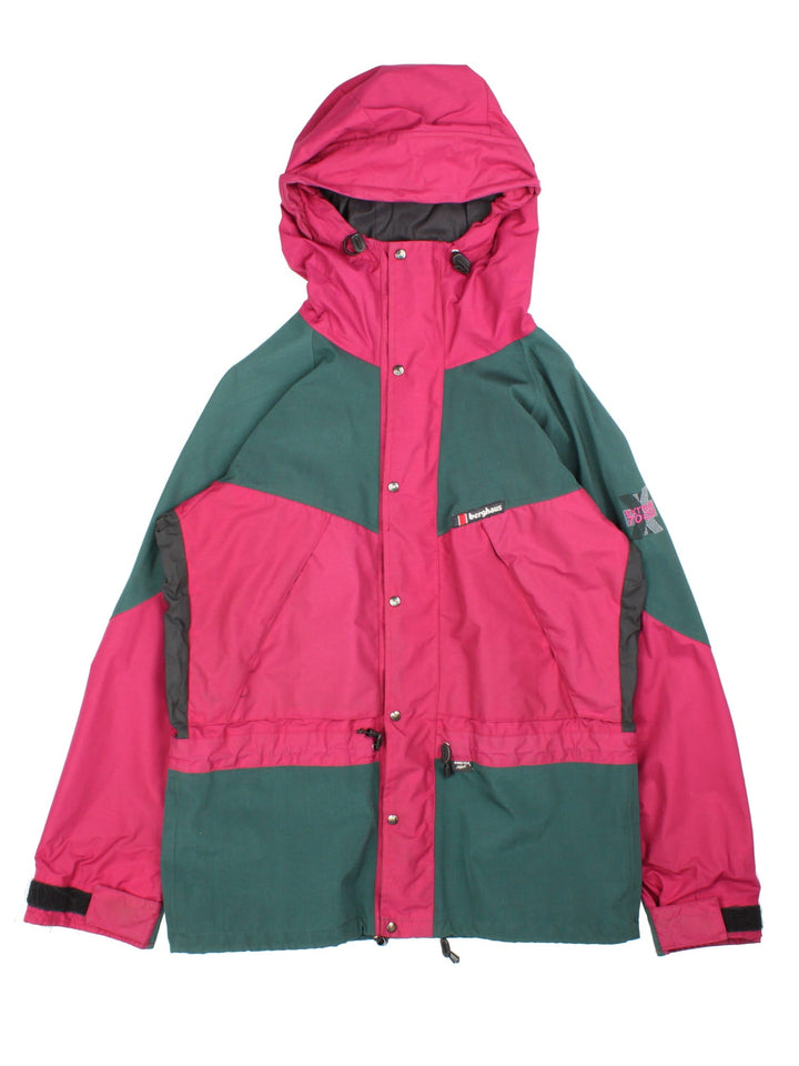 Vintage Berghaus Extrem 7000 Coat in a burgundy red and dark green colourway. The jacket is water proofed with gore-tex, and a mesh lining, and multiple pockets inside and out. There is a toggle to pull in the waist and zip to fasten. 