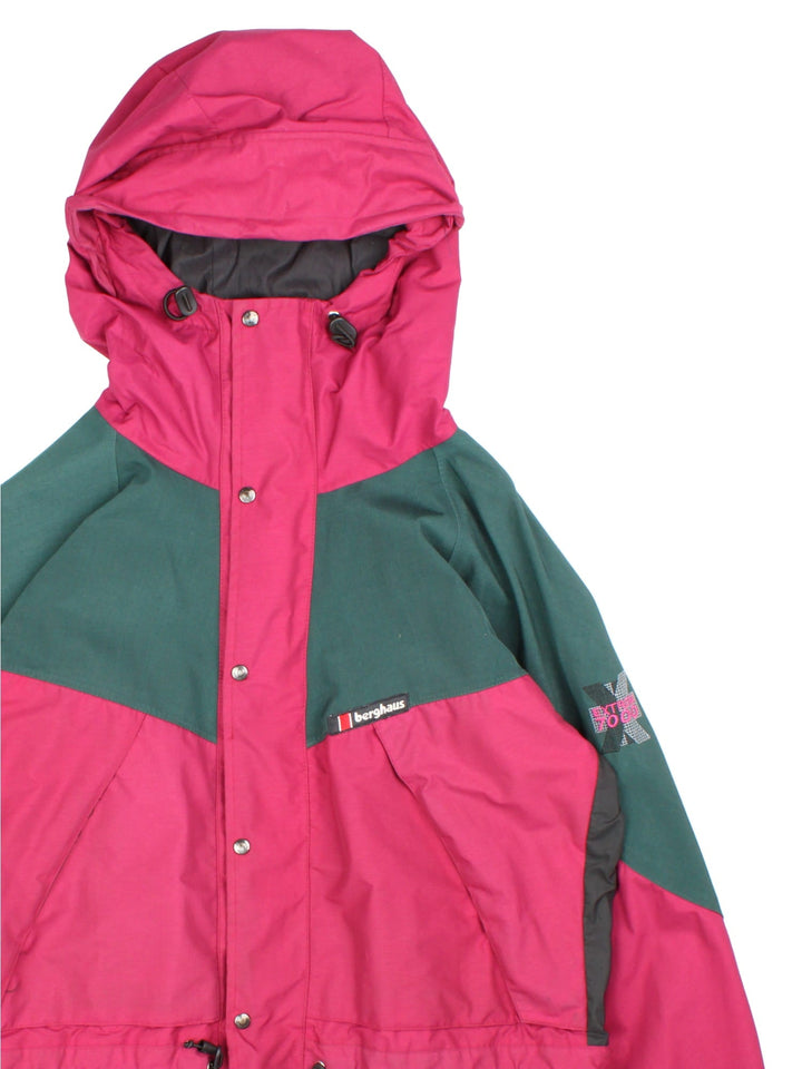 Vintage Berghaus Extrem 7000 Coat in a burgundy red and dark green colourway. The jacket is water proofed with gore-tex, and a mesh lining, and multiple pockets inside and out. There is a toggle to pull in the waist and zip to fasten. 