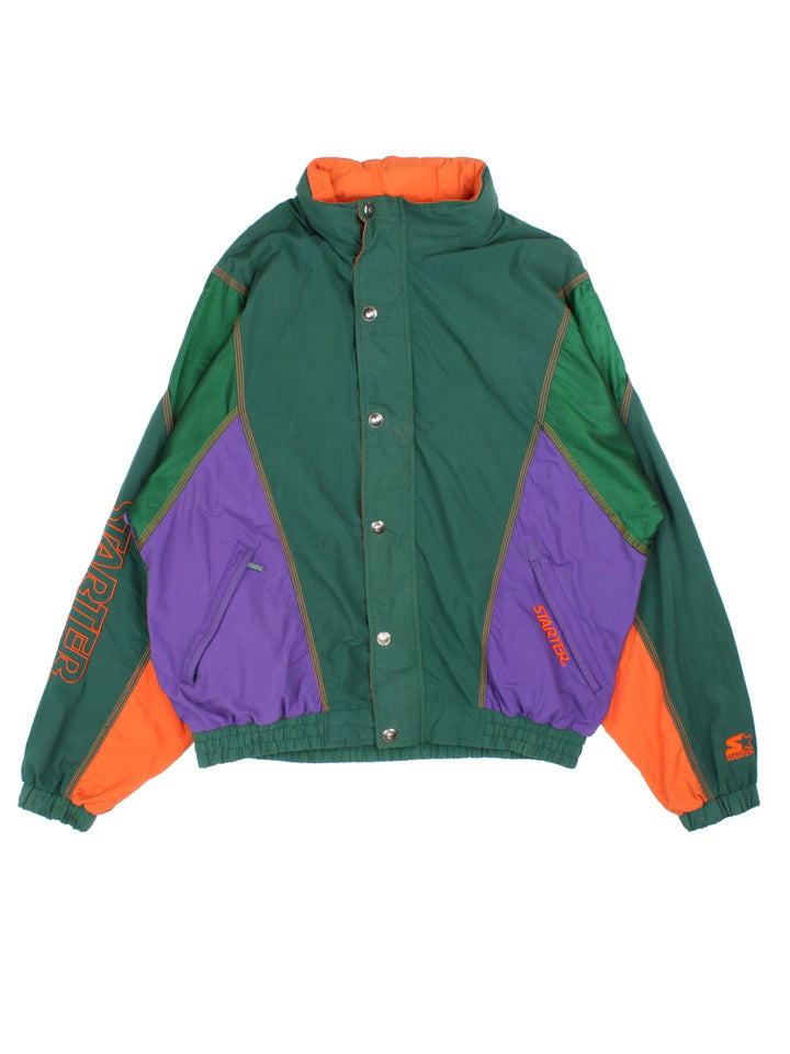 Vintage 1990s Starter Starter sports jacket in a green, orange and purple colourway. The jacket has multiple embroidered logos and graphics, a batwing sleeve shape and two zipped jetted pockets on the front. 