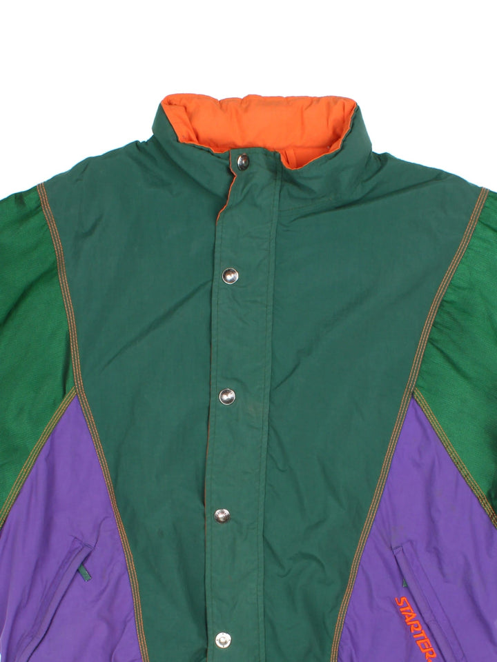 Vintage 1990s Starter Starter sports jacket in a green, orange and purple colourway. The jacket has multiple embroidered logos and graphics, a batwing sleeve shape and two zipped jetted pockets on the front. 