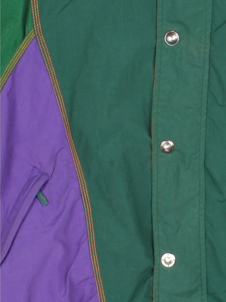 Vintage 1990s Starter Starter sports jacket in a green, orange and purple colourway. The jacket has multiple embroidered logos and graphics, a batwing sleeve shape and two zipped jetted pockets on the front. 