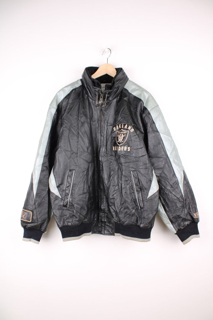 Vintage 90s Oakland Raiders leather jacket. Features embroidered badge on the front and back, and a pack away hood. 