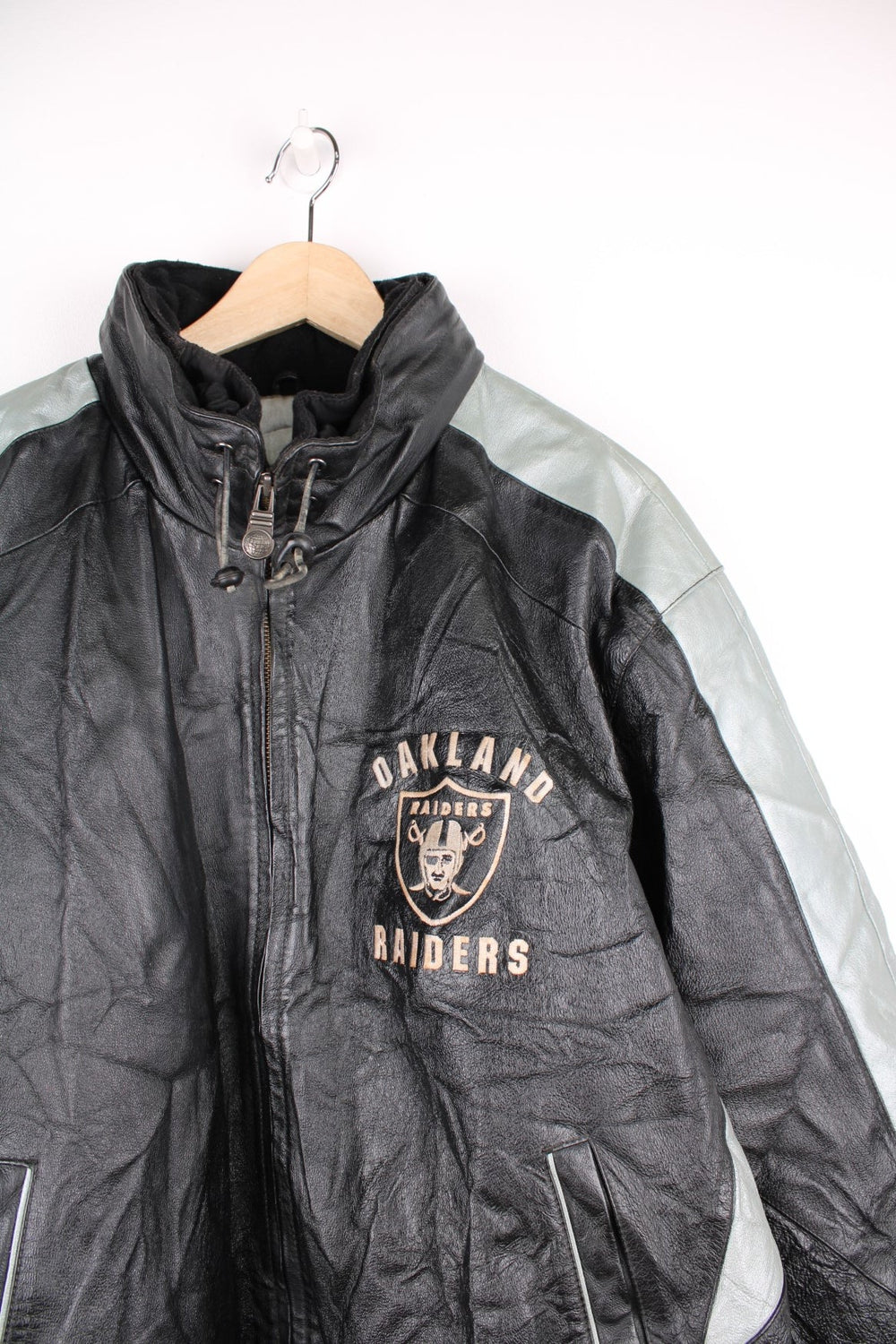 Vintage 90s Oakland Raiders leather jacket. Features embroidered badge on the front and back, and a pack away hood. 