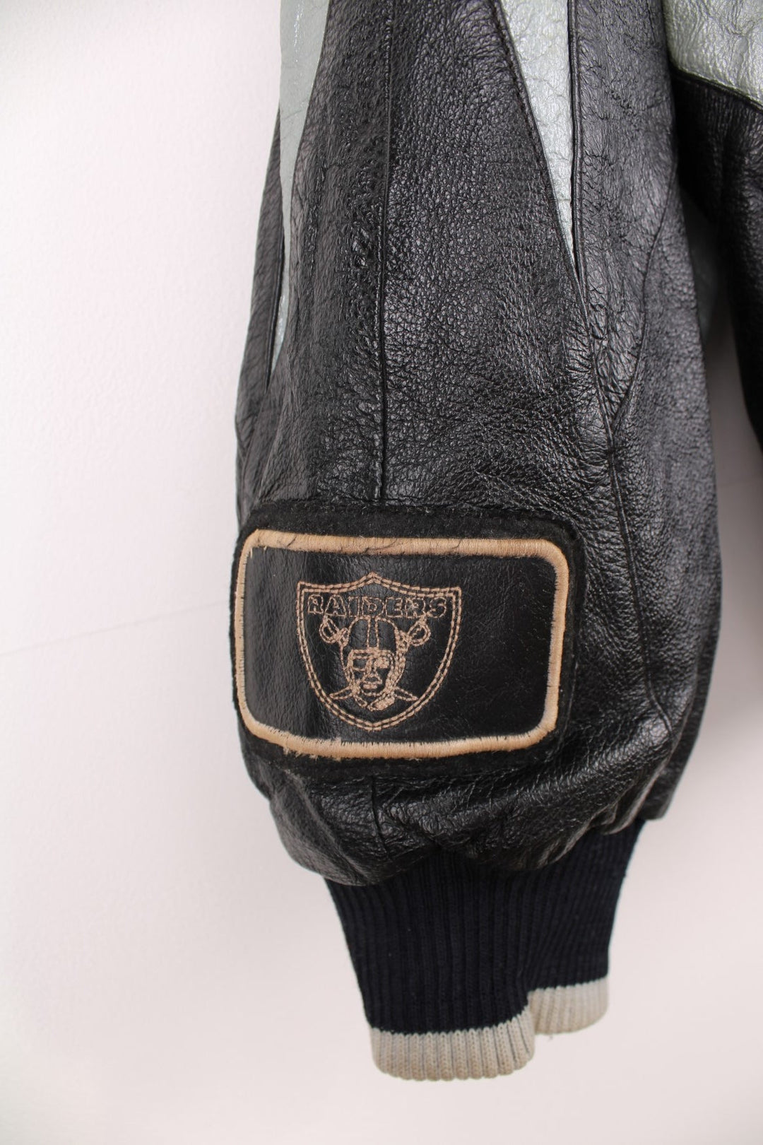 Vintage 90s Oakland Raiders leather jacket. Features embroidered badge on the front and back, and a pack away hood. 