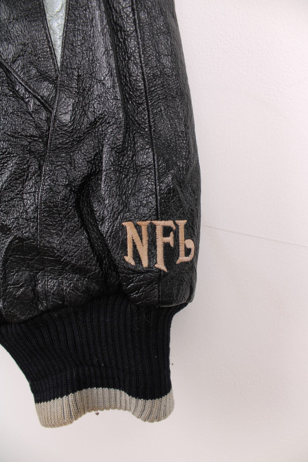 Vintage 90s Oakland Raiders leather jacket. Features embroidered badge on the front and back, and a pack away hood. 