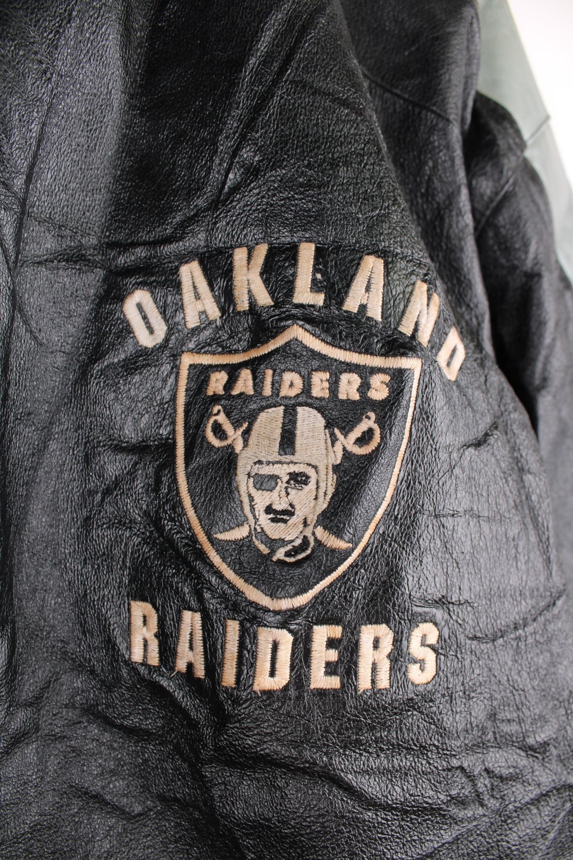 Vintage 90s Oakland Raiders leather jacket. Features embroidered badge on the front and back, and a pack away hood. 