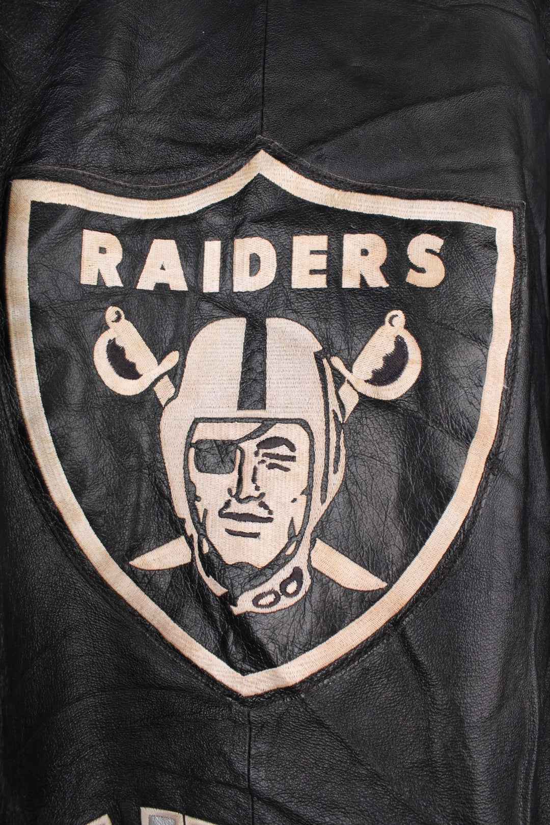 Vintage 90s Oakland Raiders leather jacket. Features embroidered badge on the front and back, and a pack away hood. 