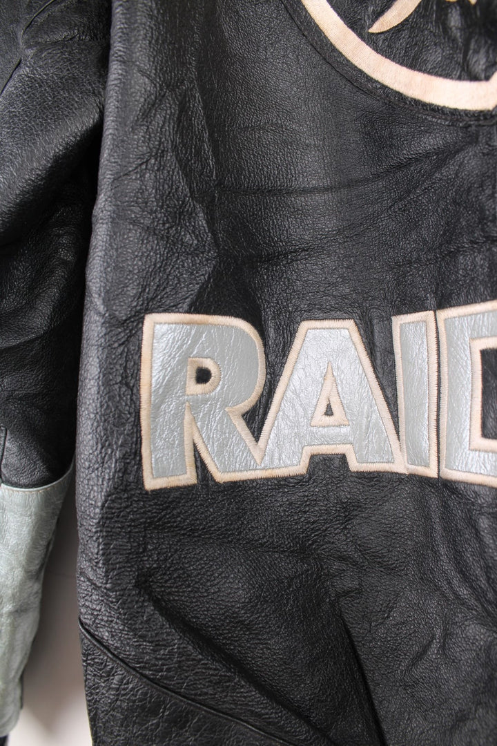 Vintage 90s Oakland Raiders leather jacket. Features embroidered badge on the front and back, and a pack away hood. 