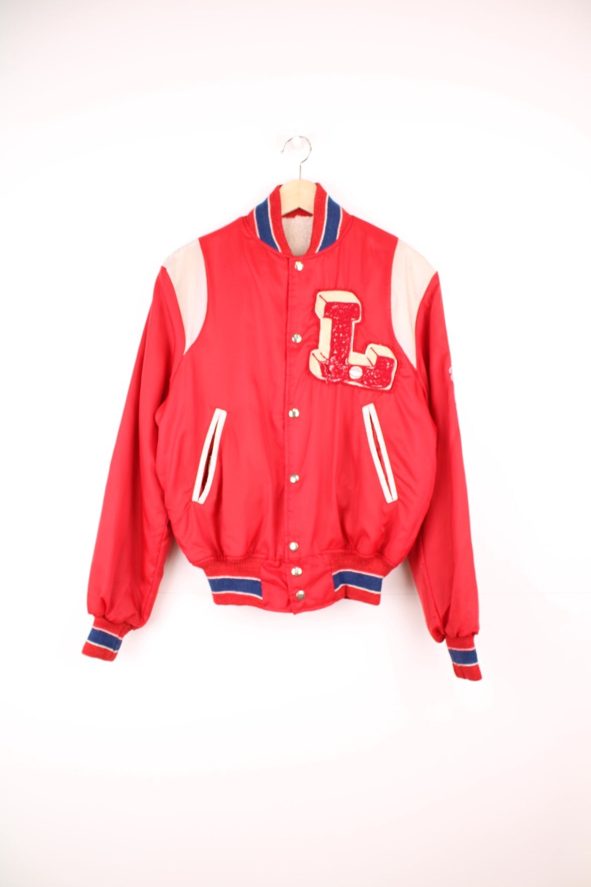 Red sherpa lined zip-through bomber jacket with blue and white accents, snap closure, slit pockets, sleeve embroidery and a large raised letter L patch.