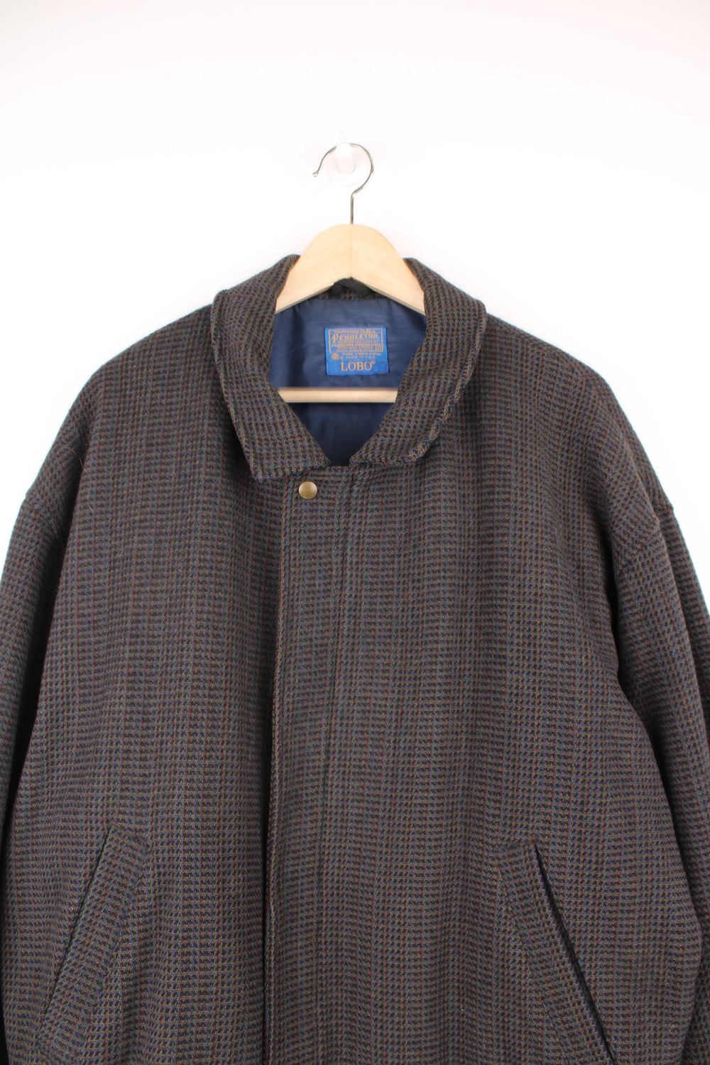 100% wool bomber-style jacket by Pendleton in brown/grey/red/purple/blue weave. Zip and snap closure, and two side pockets.   