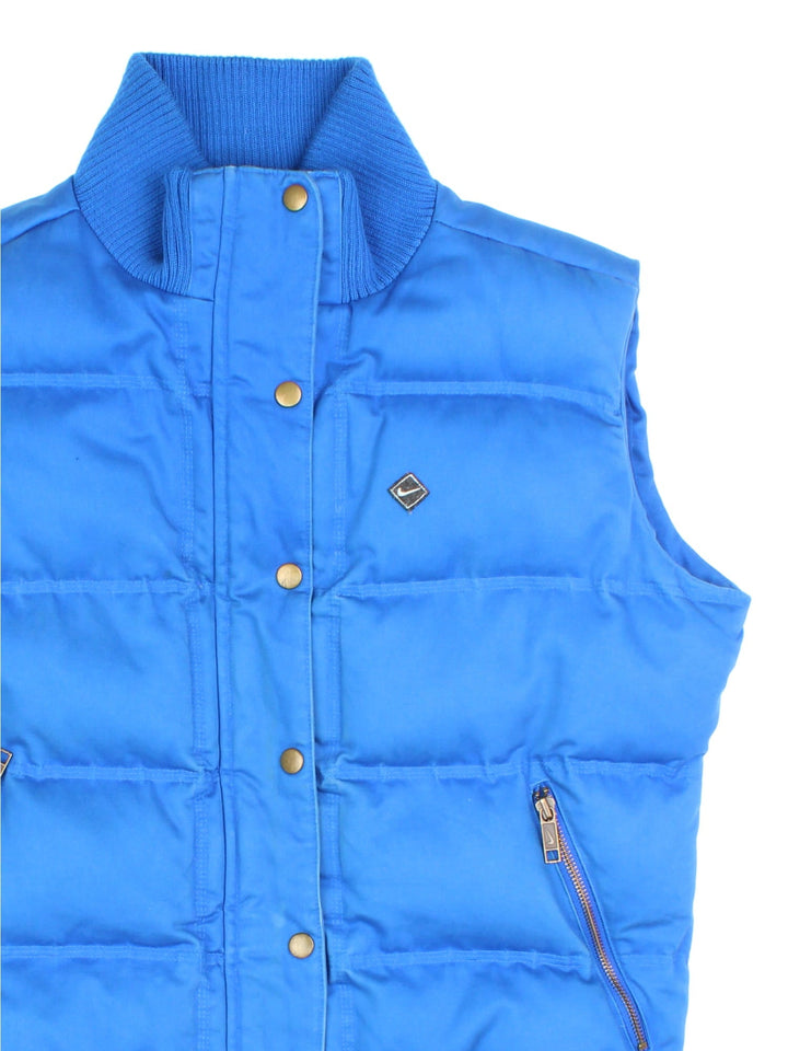 Vintage Y2K Nike Trail Gilet in a blue colourway. Button and zip fastetening with zip side pockets, insulated with branded quilted lining, and swoosh logo embroidered on the front.