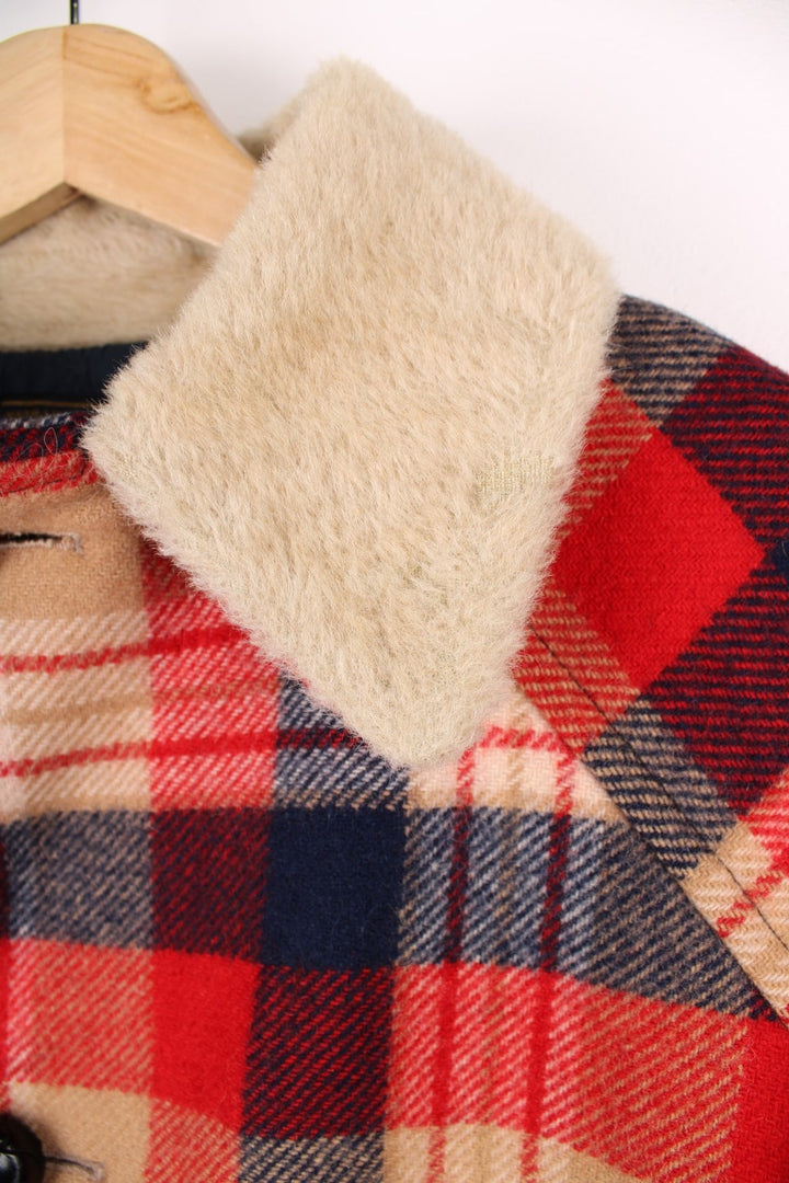 Vintage Pendleton coat in a red navy and cream checked Wool. The jacket has a faux fur collar, is lined with a quilted polyester, and has 2 jetted pockets on the front panels. Made in the USA. 