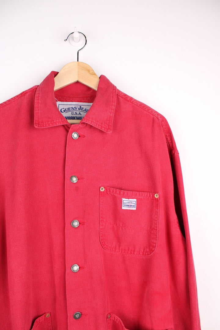 Vintage Guess Jeans Chore Jacket in washed red colourway. The jacket has 3 pockets on the front panels with rivets to secure, and a tool loop. Made in the USA.  