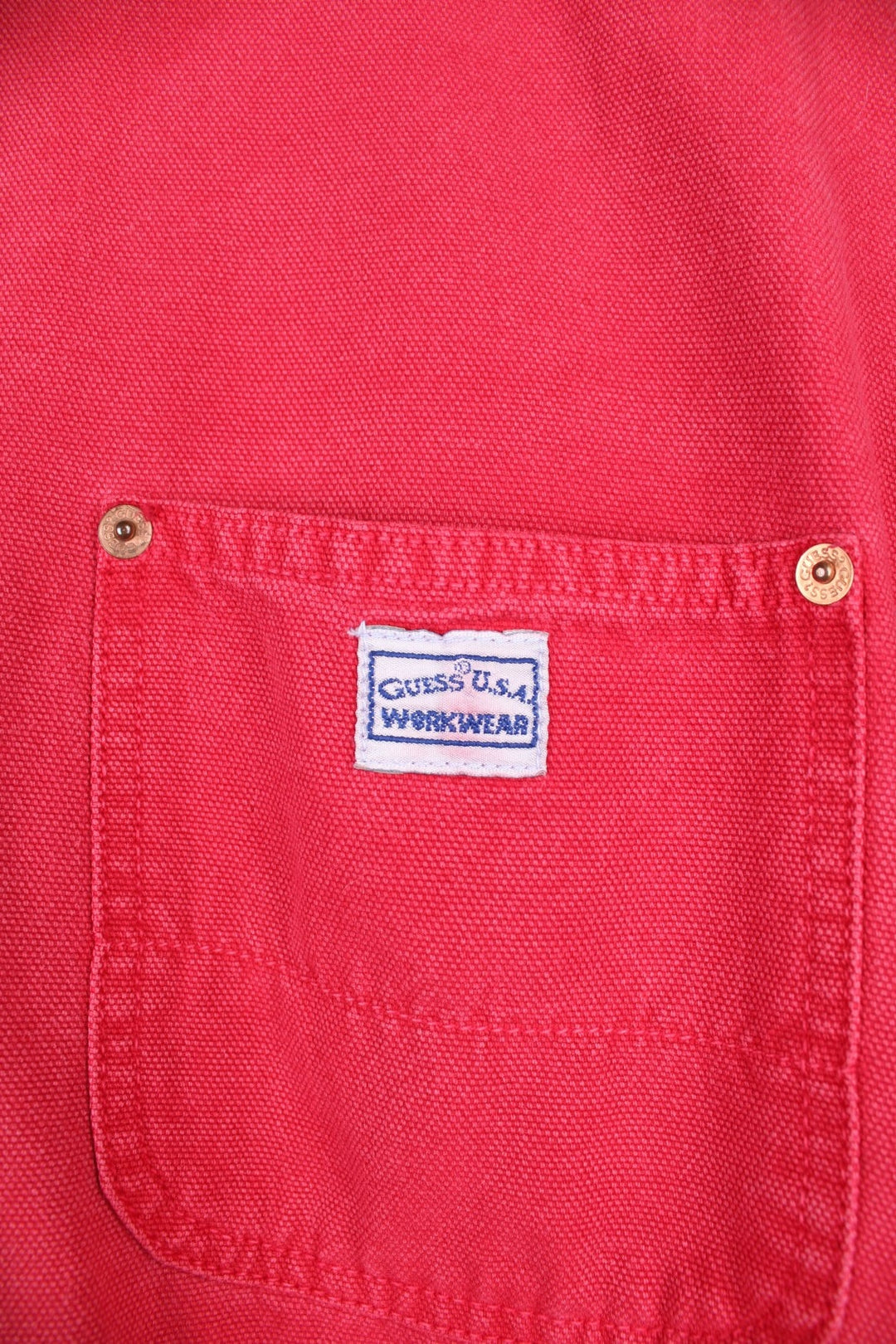 Vintage Guess Jeans Chore Jacket in washed red colourway. The jacket has 3 pockets on the front panels with rivets to secure, and a tool loop. Made in the USA.  