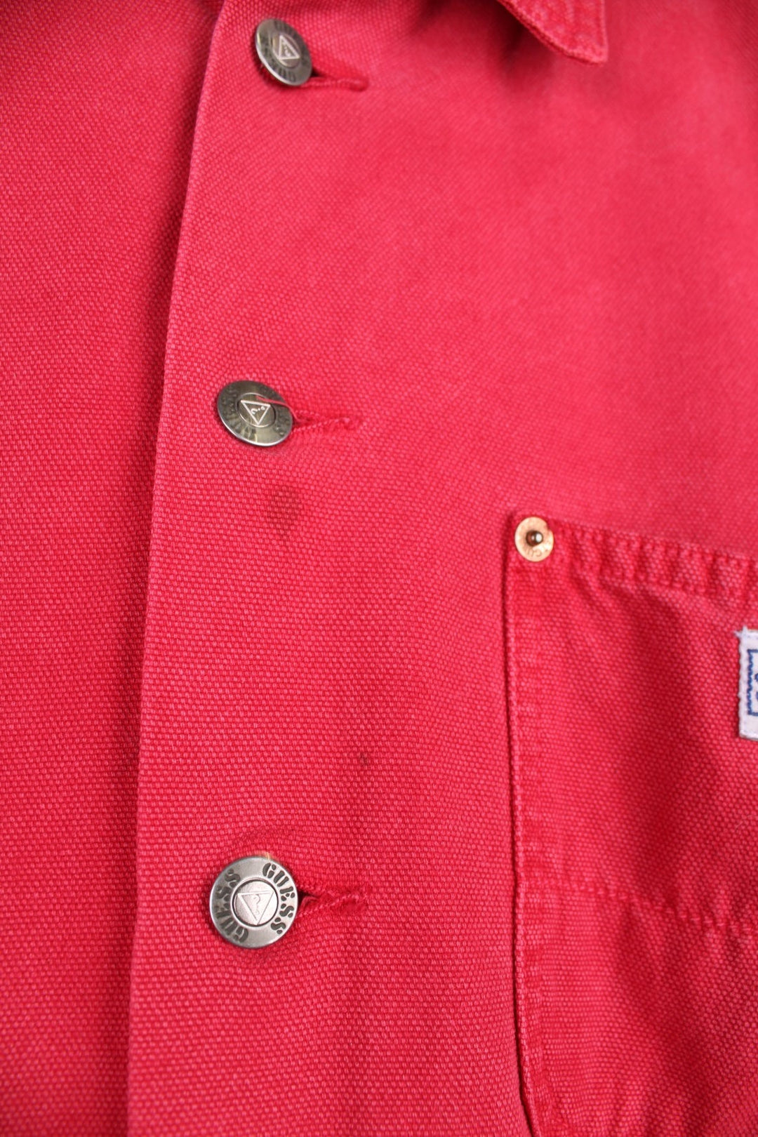 Vintage Guess Jeans Chore Jacket in washed red colourway. The jacket has 3 pockets on the front panels with rivets to secure, and a tool loop. Made in the USA.  