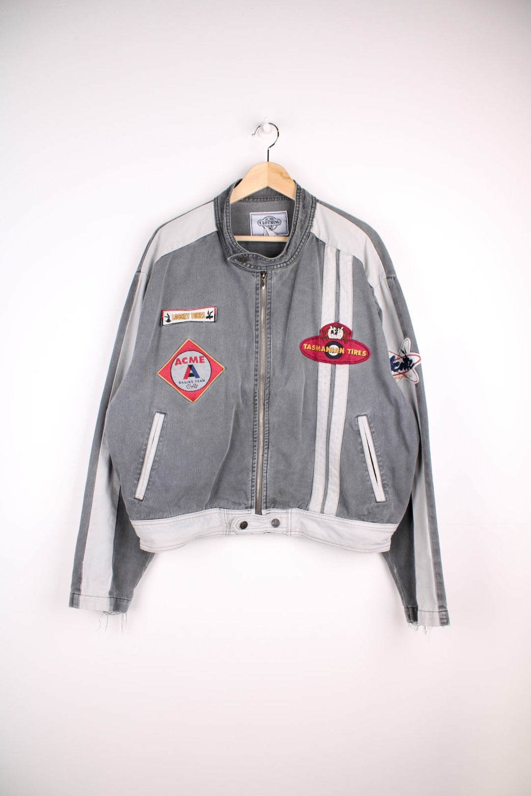 Vintage ACME Clothing & Looney Tunes denim jacket in a grey colourway. The jacket has stitched on patches, and racing stripes on the front, a classic motorcycle jacket collar and a large embroidered design of Buggs Bunny on the back. 