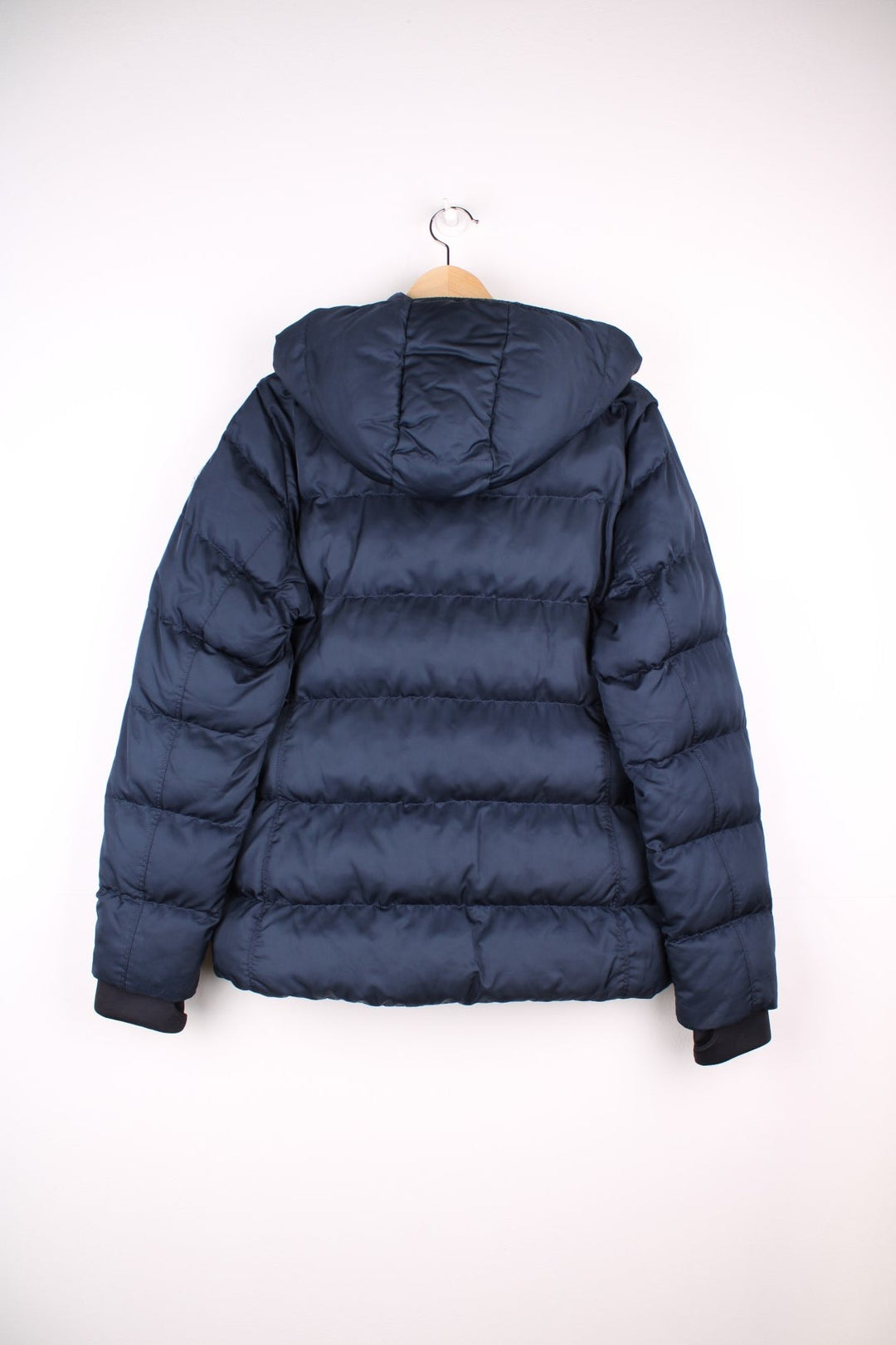 Moncler Cardere down puffer coat in a navy blue colourway. The coat has a puffer lining and the Moncler logo embroidered around the collar. There are extra thermal lined cuffs and a double zip for extra warmth.  