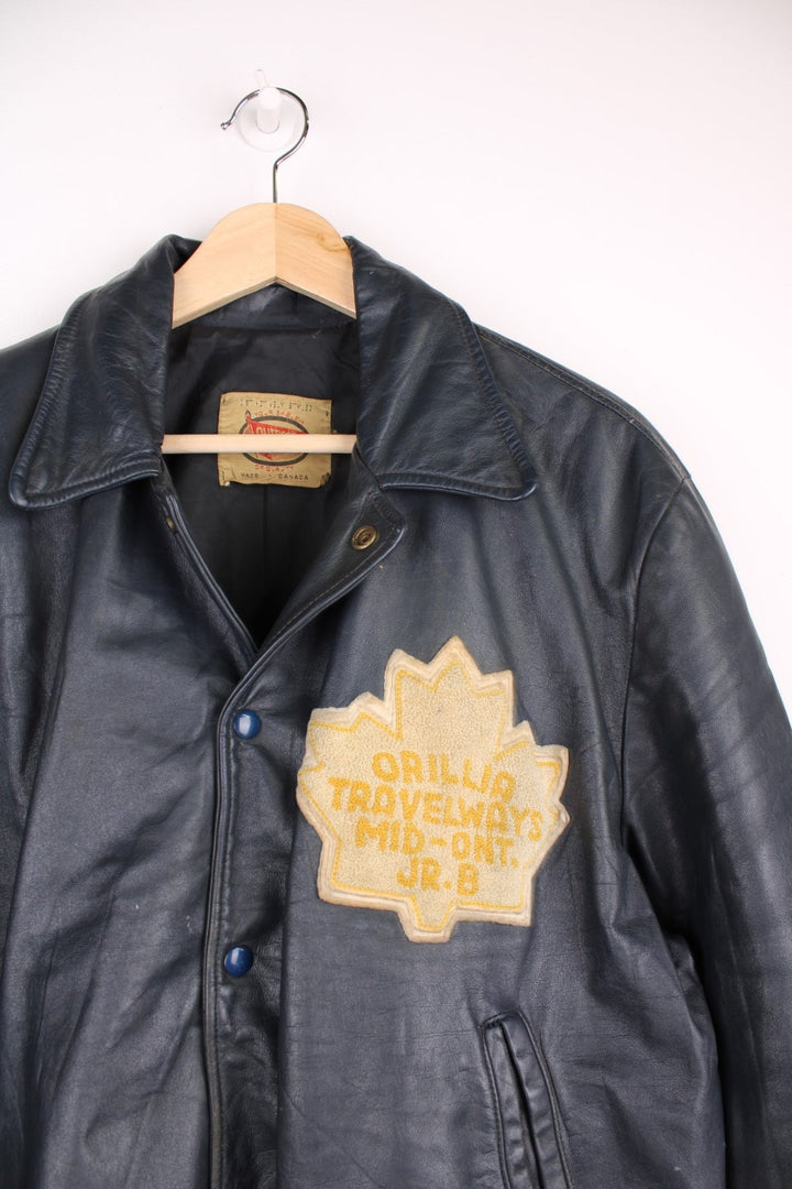 Vintage leather jacket in a dark navy blue colourway. The jacket has an Orillia Travelways patch, who were an Ice Hockey team based in Ontario Canada. It also has press studs to close, and jetted pockets on the front. Dates between 1970-78. Made in Canada. 