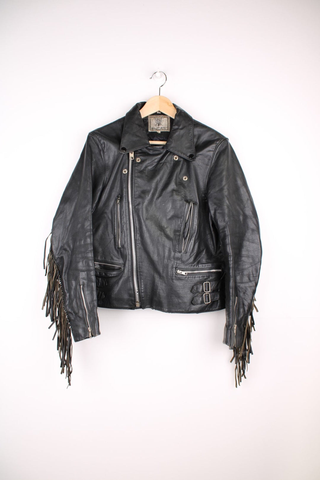 Vintage fringed motorcycle jacket in black. The jacket dates to the 1980s from the brand Drag Specialties. It is made from a heavyweight leather and has fringe up the seam of the sleeves and across the yoke panel. 