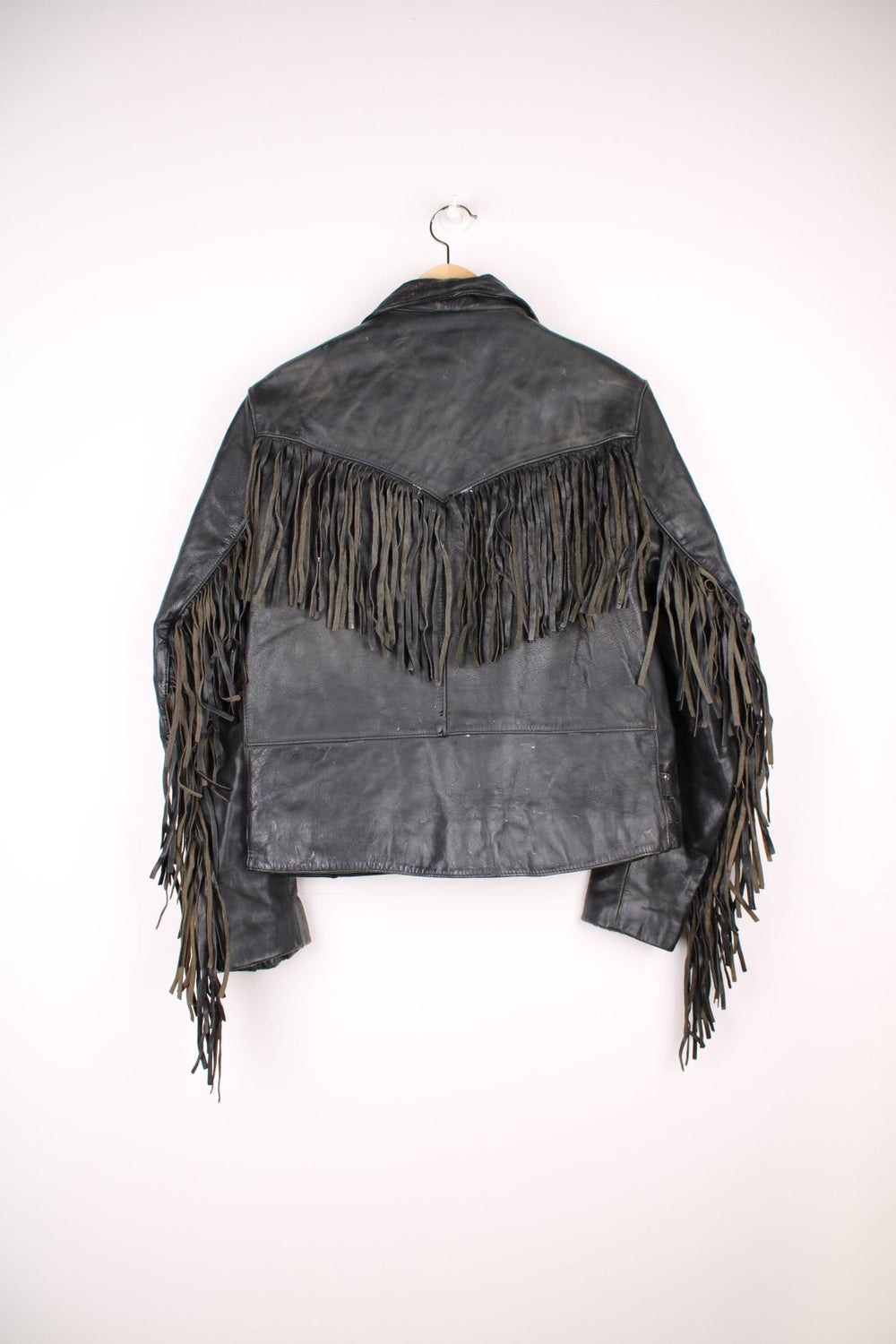 Vintage fringed motorcycle jacket in black. The jacket dates to the 1980s from the brand Drag Specialties. It is made from a heavyweight leather and has fringe up the seam of the sleeves and across the yoke panel. 