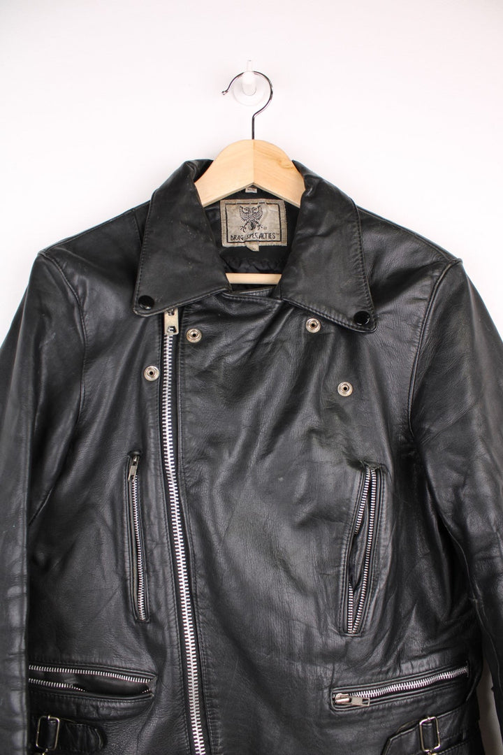 Vintage fringed motorcycle jacket in black. The jacket dates to the 1980s from the brand Drag Specialties. It is made from a heavyweight leather and has fringe up the seam of the sleeves and across the yoke panel. 