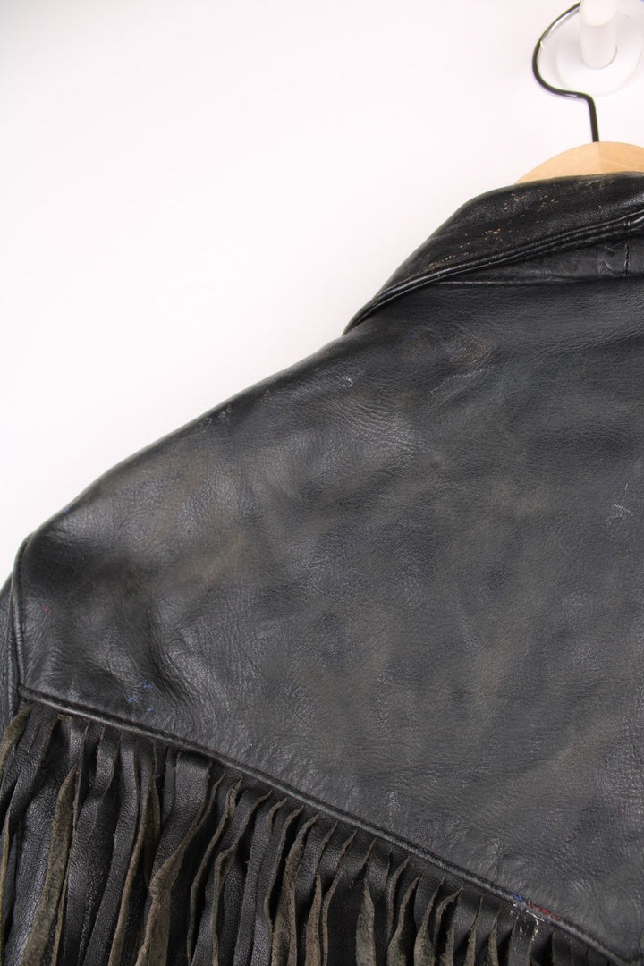 Vintage fringed motorcycle jacket in black. The jacket dates to the 1980s from the brand Drag Specialties. It is made from a heavyweight leather and has fringe up the seam of the sleeves and across the yoke panel. 