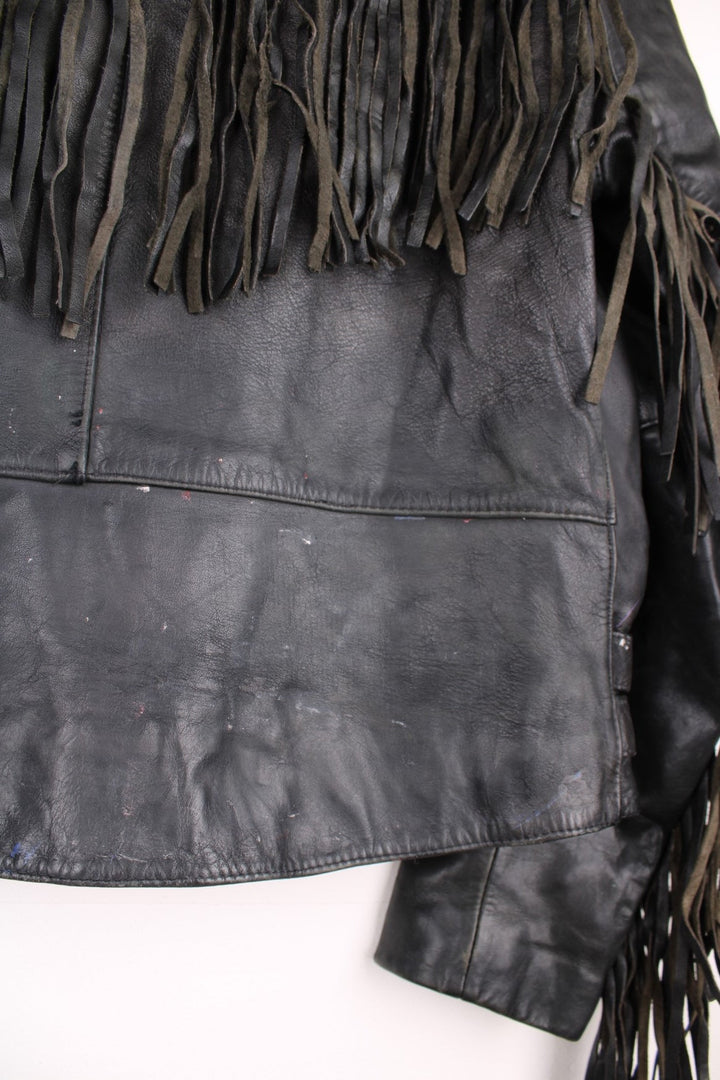 Vintage fringed motorcycle jacket in black. The jacket dates to the 1980s from the brand Drag Specialties. It is made from a heavyweight leather and has fringe up the seam of the sleeves and across the yoke panel. 