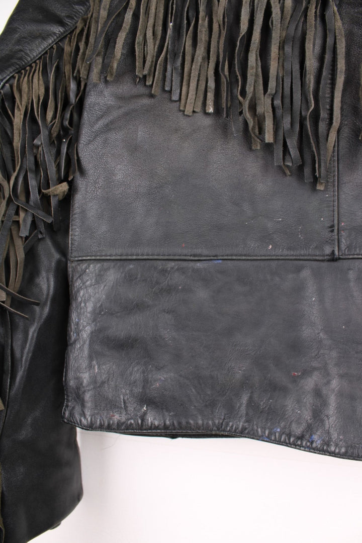 Vintage fringed motorcycle jacket in black. The jacket dates to the 1980s from the brand Drag Specialties. It is made from a heavyweight leather and has fringe up the seam of the sleeves and across the yoke panel. 