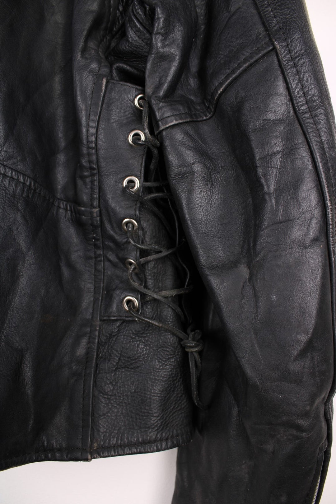 Vintage black leather motorcycle jacket. The interior label says Hot Leathers, and has lace up side panels, multiple pockets and a belt. 