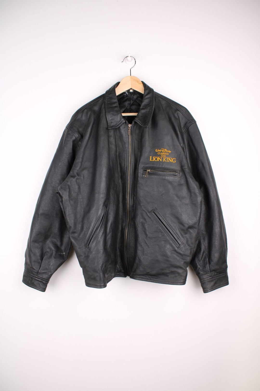 Vintage 1994 Disney Lion King Promo Leather Jacket in black. The jacket has a dagger collar, Lion King logo embroidered on the front panel and an interior pocket. The jacket is also lined with a quilted satin fabric. 