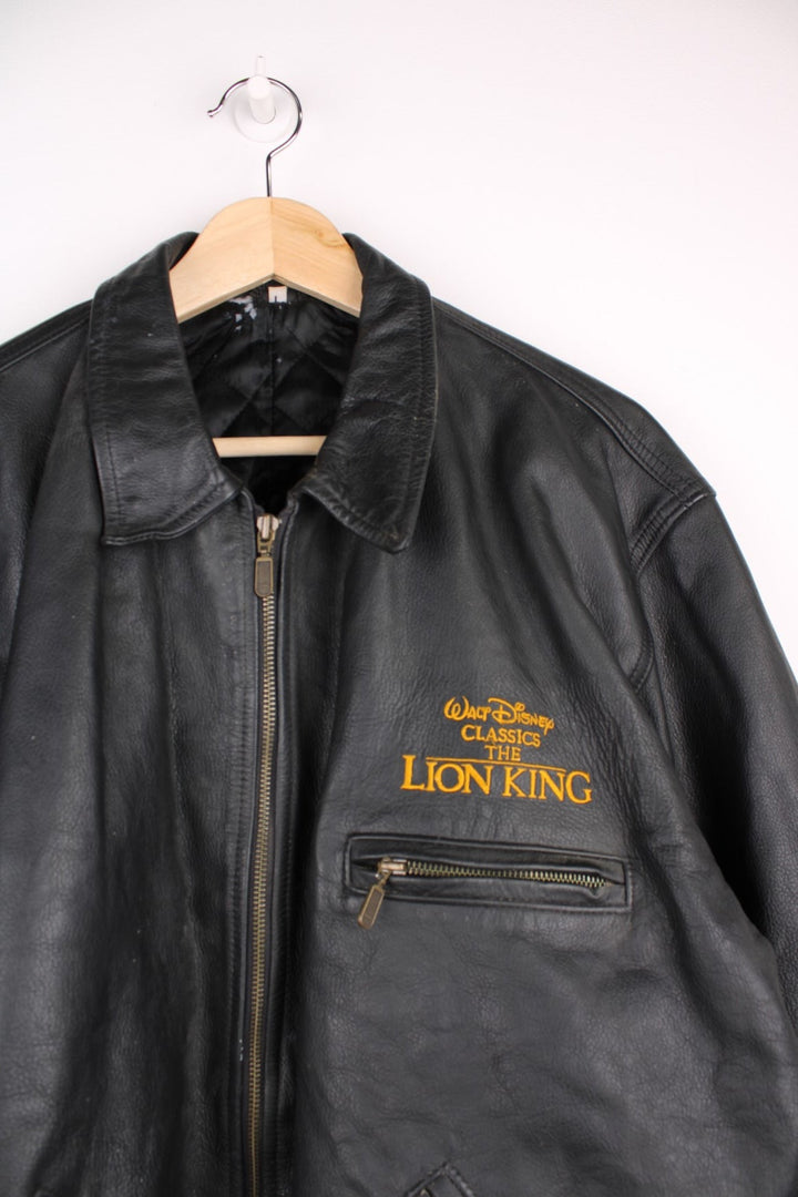 Vintage 1994 Disney Lion King Promo Leather Jacket in black. The jacket has a dagger collar, Lion King logo embroidered on the front panel and an interior pocket. The jacket is also lined with a quilted satin fabric. 