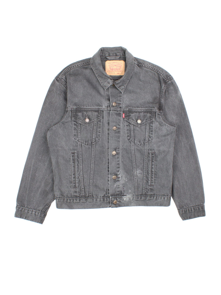 Levi Strauss denim trucker jacket in black with four pockets, button closure, and a red tab on the front.