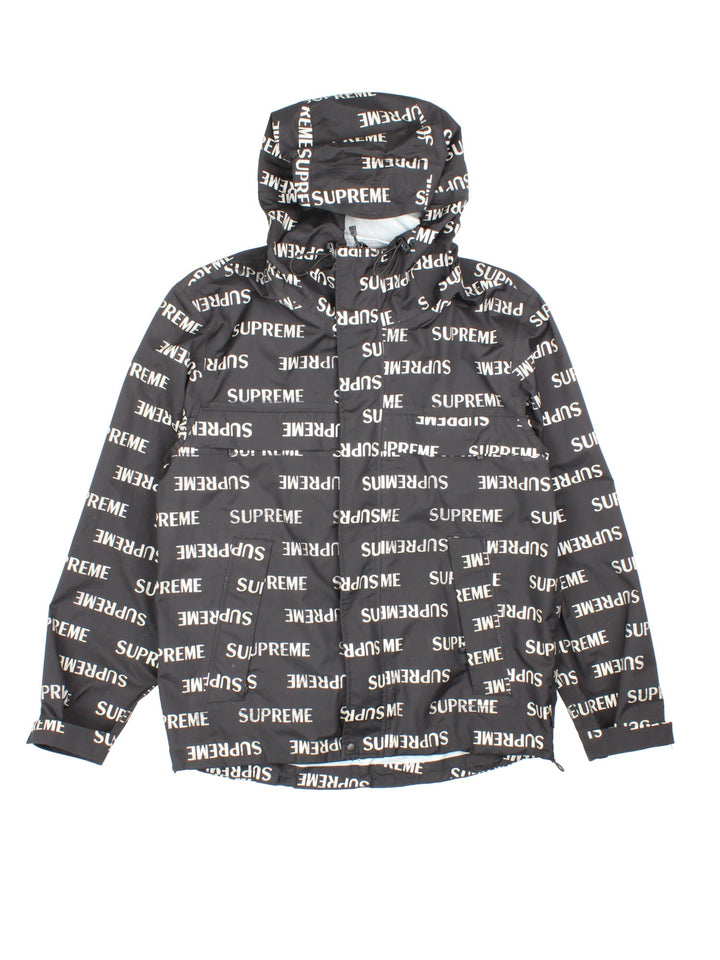 Supreme 3M reflective repeat logo taped seam waterproof jacket in black with zip and snap closure, and a hood with elastic toggle adjusters.