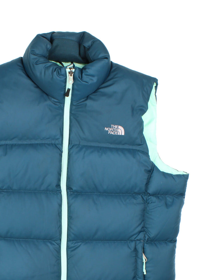 The North Face 700 down zip-through puffer gilet in blue with mint green lining and hardware, two zipped pockets, and embroidered logos front and back.