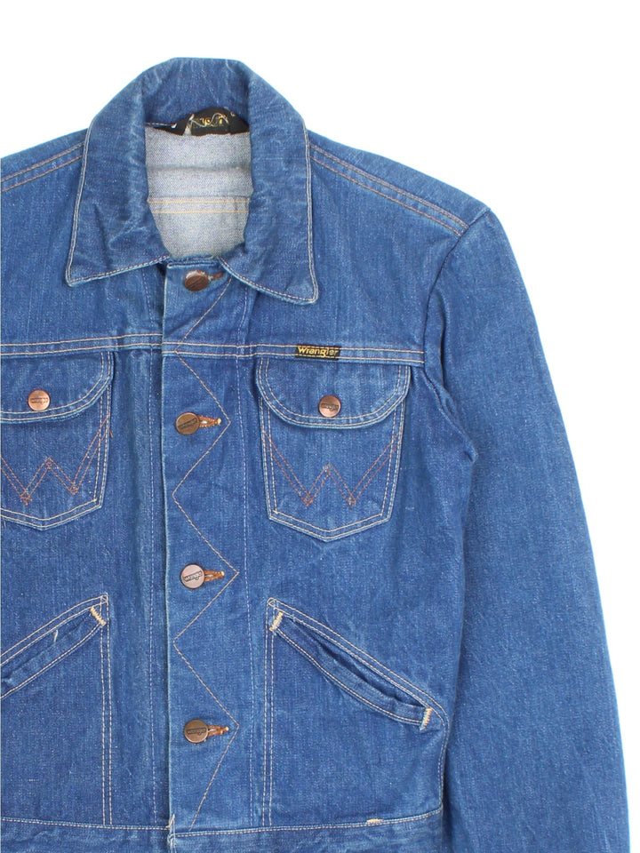 Vintage Wrangler Denim Jacket in a blue colourway. Buttons up and has multiple pockets, contrast cross stitching throughout, and has the logo tab embroidered on the front.