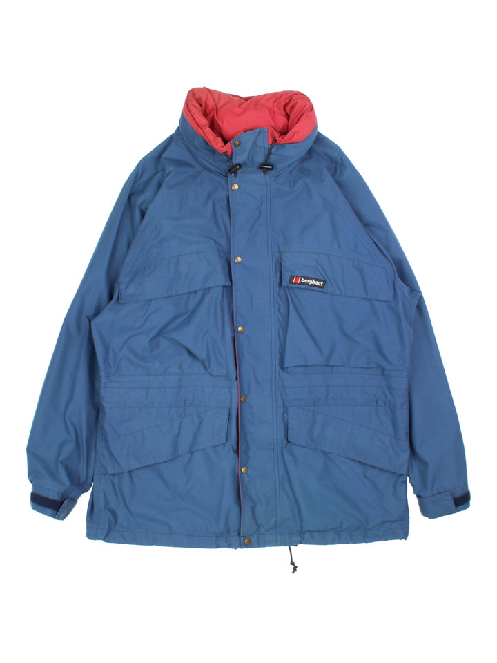 Vintage Berghaus Jacket in a blue colourway. Zips and buttons up, has multiple pockets, hidden hood, and the logo embroidered on the front.