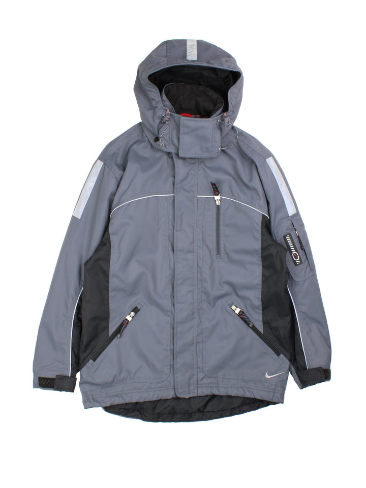 Vintage Nike Y2K Tech Coat in a grey colourway. Zips up and has multiple pockets, insulated with a fleece lining, detachable hood, and has the swoosh logo embroidered on the front and back.